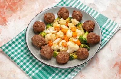bottom-view-broccoli-cauliflower-salad-meatball-plate-green-white-checkered-napkin-nude-isolated-background_11zon