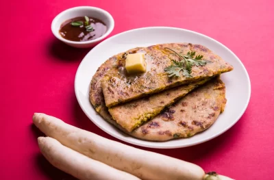 daikon-radish-mooli-stuffed-paratha-served-plate-with-butter-tomato-ketchup-colourful-wooden-background-selective-focus_11zon