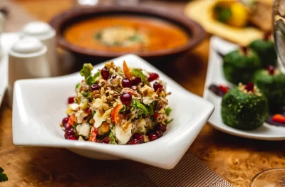 side-view-walnut-salad-with-pomegranate-bell-pepper-mayo-greens-meat-lettuce-plate